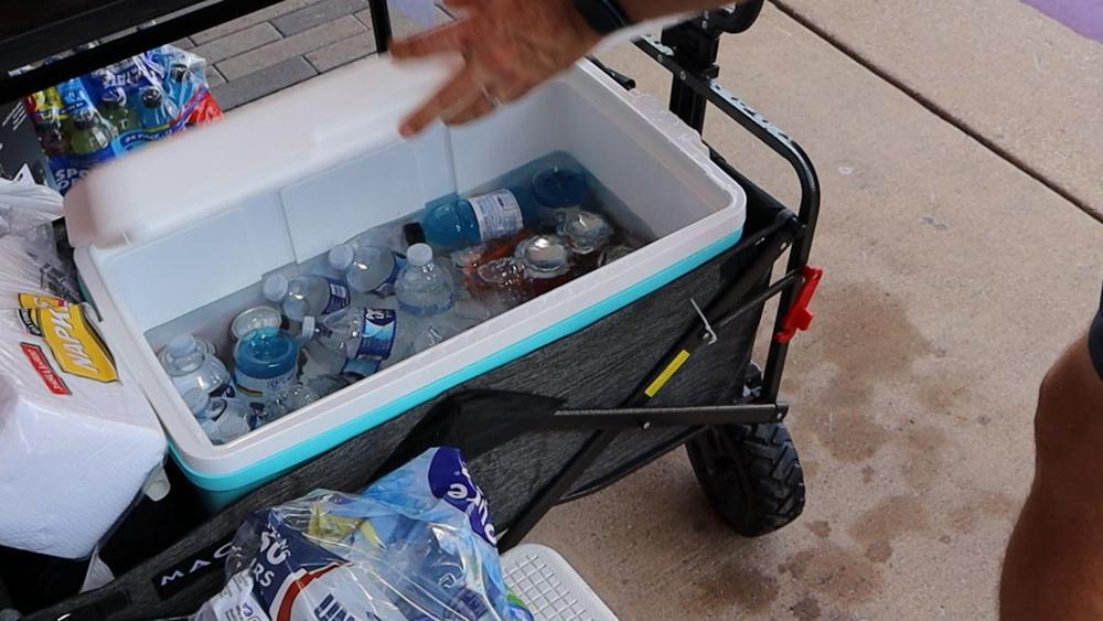 Cooler of bottled water and Gatorade in a wagon on the sidewalk.