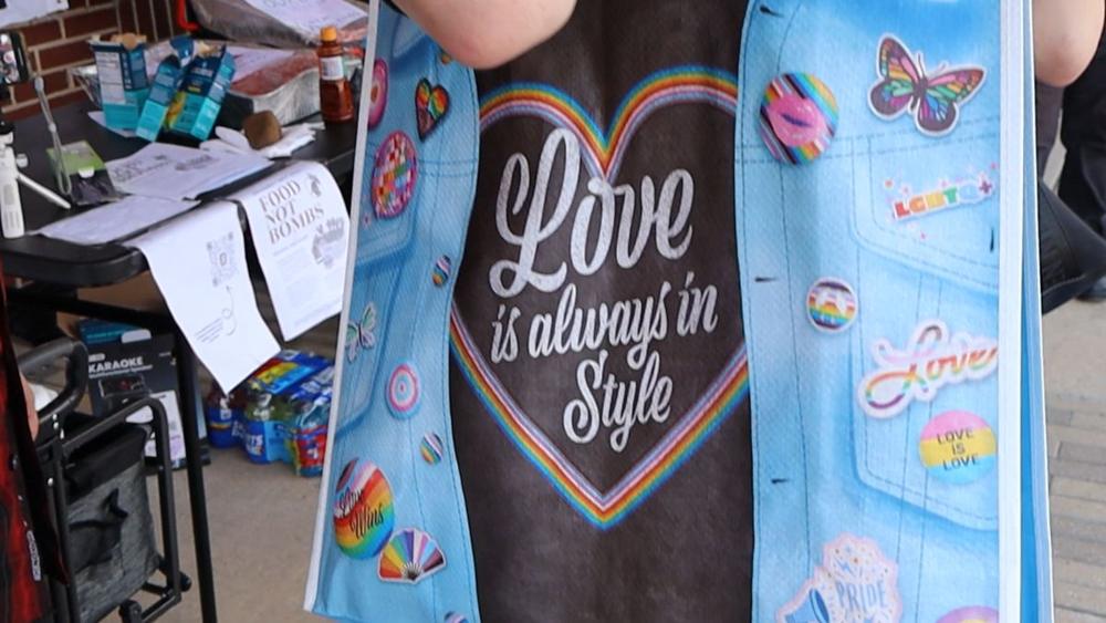 Denim-print apron reading Love is always in Style covered in Pride stickers.