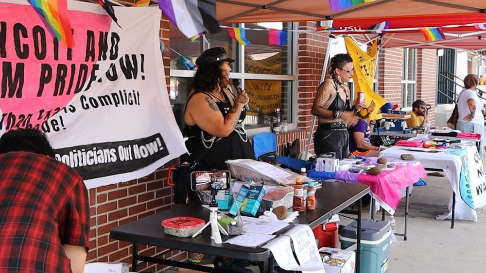 Wide view of the coalition tent with food table, first-aid table and microphone.